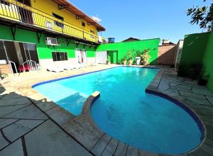 a swimming pool in front of a green building at Hospedagem Riazo in Pirenópolis