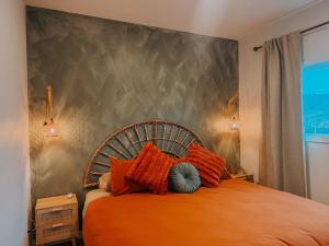 a bedroom with an orange bed with a large headboard at Private Boho Tiny Home - Lakes, Wineries, Hike, Ski in Kelowna