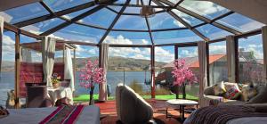 a glass room with a view of the water at Titicaca Mia Lodge Perú in Puno