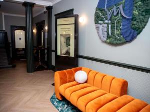 an orange couch with a white ball on top of it at Mercure Thurrock Stifford Hall in Grays Thurrock