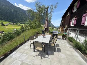 a patio with a table and chairs and an umbrella at Bühelhus in Dalaas