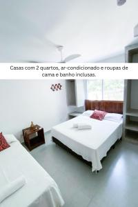 two beds in a white room with at Cond Vista Hermosa - Casas para famílias 2 quartos in Pipa