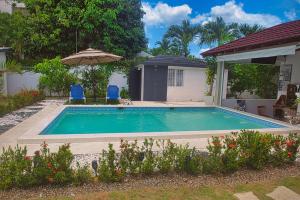 a swimming pool with two chairs and an umbrella at Villa La Dueña Las Terrenas in Las Terrenas