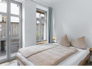 a white bedroom with a bed and two windows at Lee in Wismar