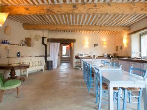 a kitchen with a long table and blue chairs at Le Serre des Granges Plus in Montaulieu