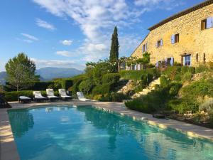 a swimming pool in front of a building with chairs around it at Le Serre des Granges Plus in Montaulieu