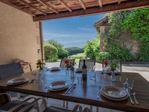 a wooden table with plates and glasses and a bottle of wine at Grande Gite Bassoues in Bassoues