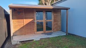 a wooden shed with a door on the grass at The Central Apartment in Geraldine