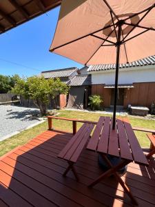 a wooden bench with an umbrella on a deck at Kia Ora Setouchi in Shodoshima