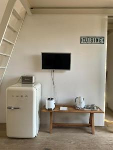 a room with a refrigerator and a tv on a wall at Casottino presso residenza Rosso di Sera in Capoliveri