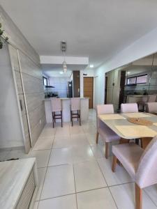 a dining room with tables and chairs and a kitchen at Apartamento com suite in Parnamirim