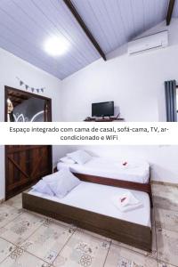 a bedroom with a bed and a television in a room at Chalé Kamala com quintal - Perfeito para Nômades Digitais in Pipa