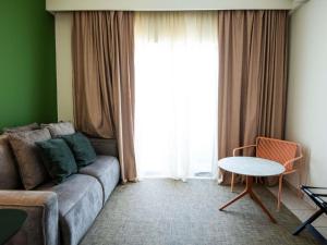 a living room with a couch and a table and a window at Ibis Styles Cayenne Centre Amazonia in Cayenne