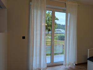 a window with white curtains and a view of a bridge at Apartmány Villa Vician in Piešťany