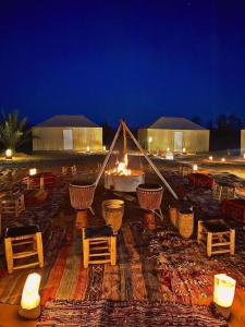a tent with a fire pit with tables and chairs at Touareg Desert Camp Erg Chigaga in El Gouera