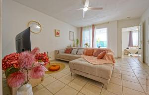 a living room with a couch and a flat screen tv at Nid rose paradis secret au robert avec jacuzzi in Le Robert