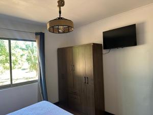 a bedroom with a flat screen tv and a cabinet at Quincho la Beli in Chillán
