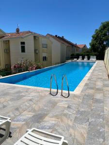 a swimming pool with two lawn chairs next to a house at Adriadome Sky in Bijela