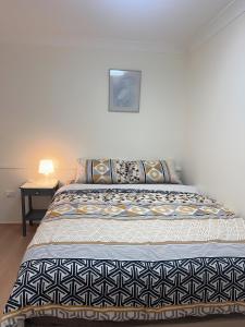 a bedroom with a bed and a table with a lamp at Private Rm4-Queen bed in Elderslie