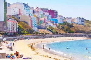 a group of people on a beach with buildings at Casa Atalaya en Malpica in Malpica