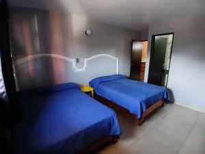 two beds in a room with blue sheets at Hotel Santa María in Mazatlán