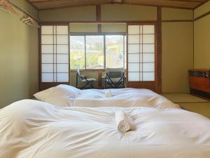 two white beds in a room with a window at Hakuba Hospitality Inn YUKINOSO in Hakuba +99 photos