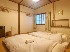 two white beds in a room with a window at Hakuba Hospitality Inn YUKINOSO in Hakuba