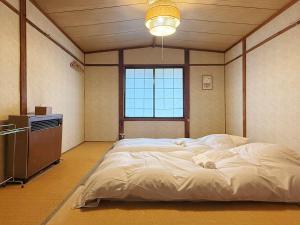 a large bed in a room with a television at Hakuba Hospitality Inn YUKINOSO in Hakuba