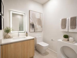 a white bathroom with a toilet and a sink at Splendid Executive Suites in Long Beach