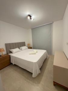 a bedroom with a large white bed with two towels on it at Feel Premiun 2408 in Asunción