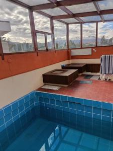 a large swimming pool with a blue tile floor and windows at Casa Junto al Rio in Arequipa +5 photos