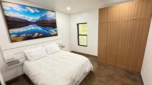 a bedroom with a bed and a painting on the wall at Glacier Luxury Retreat Oak Tree Apartment 3 in Hungry Horse