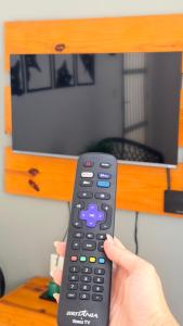 a person holding a remote control in front of a tv at Miau de Pipa in Pipa