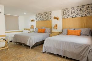 ein Zimmer mit zwei Betten und orangefarbenen Kissen in der Unterkunft Hotel Isla Real in Tierra Bomba + 154 Fotos