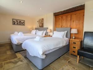 a bedroom with two beds and a chair at The Old Byres in Washford +70 photos