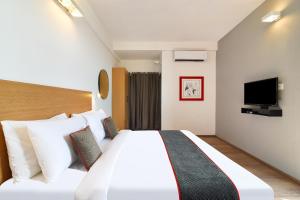 a hotel room with a large bed and a tv at Townhouse Srm Kuppakonam Pudur in Coimbatore +64 photos