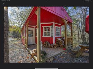 a red house with a deck with a pile of logs at Peaceful Forest Tiny Home in Newport