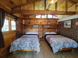 two beds in a room with wooden walls at Hospedaje Rancho La Joya in Villa del Carbón