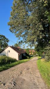 a dirt road next to a house and a tree at Pokój i Spokój in Szarki