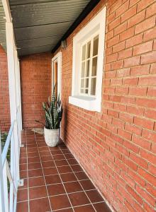 a brick wall with a potted plant next to a window at Modern retro private apartment in Polokwane