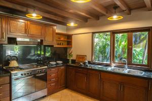 a large kitchen with wooden cabinets and a sink at Villa Layangan - Two Bedrooms with Pool Access in Sanur