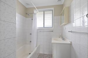 a white bathroom with a tub and a sink and a shower at Ocean Vibes in Scotts Head +32 photos