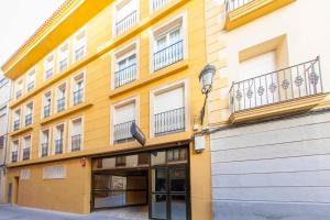 un bâtiment jaune avec des balcons sur son côté dans l'établissement Apartamentos Massò, à Albacete
