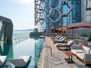 a swimming pool with lounge chairs and a building at Swissôtel Corniche Park Towers Doha in Doha