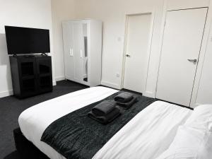 a bedroom with a bed with a black blanket and a flat screen tv at Private Flat Near City Centre in Peterborough