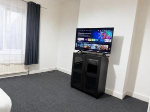 a room with a flat screen tv on top of a cabinet at Private Flat Near City Centre in Peterborough