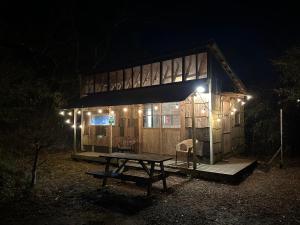 a cabin with a picnic table in front of it at night at NAT PARK Isumi RV in Iwada