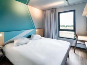 a bedroom with a large white bed and a window at ibis budget Morlaix in Morlaix +100 photos