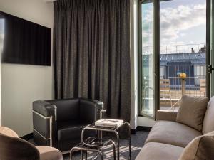 a living room with a couch and a chair and a window at Hotel Maison Hamelin Paris - Handwritten Collection in Paris