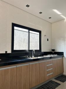 a large kitchen with a sink and a window at Maggi Residence in Batatais